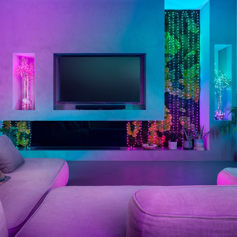 Sala de estar moderna iluminada con luces LED inteligentes Twinkly, creando una atmósfera vibrante y colorida con efectos dinámicos sobre plantas decorativas y muebles contemporáneos.