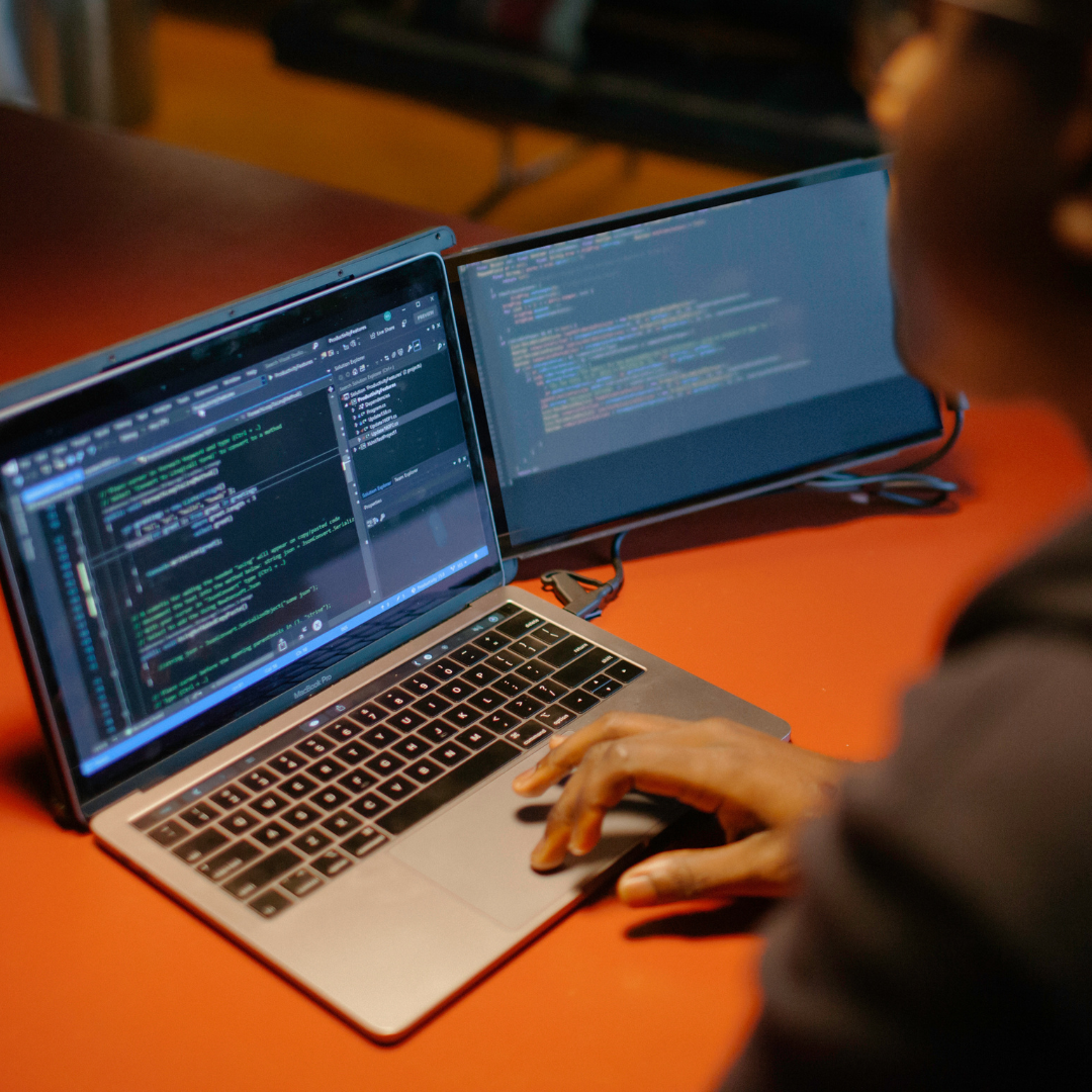 Desarrollador programando con doble pantalla usando Mobile Pixels en escritorio de oficina