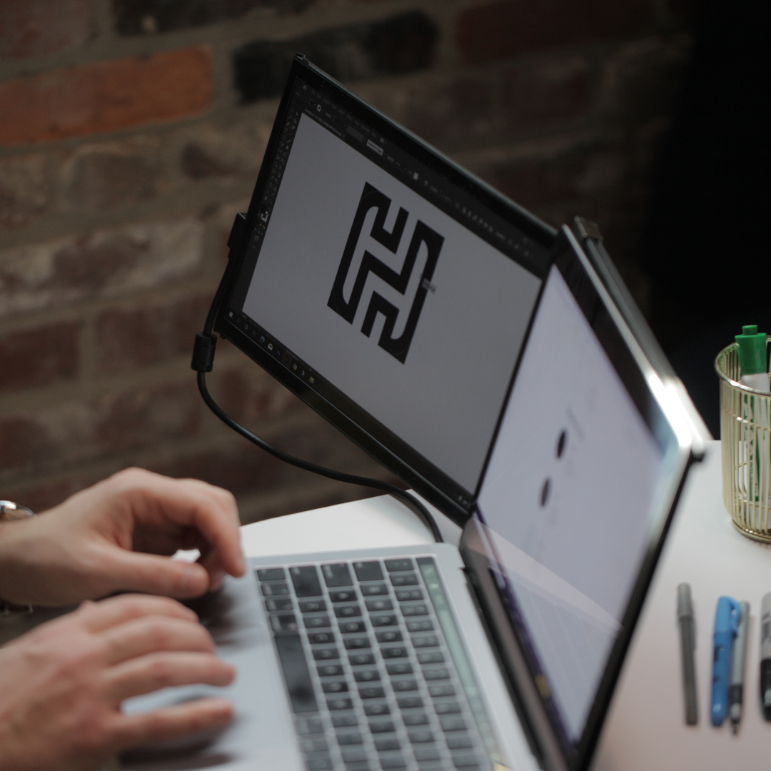 Diseñador usando monitor portátil Mobile Pixels para crear logos en software de diseño gráfico