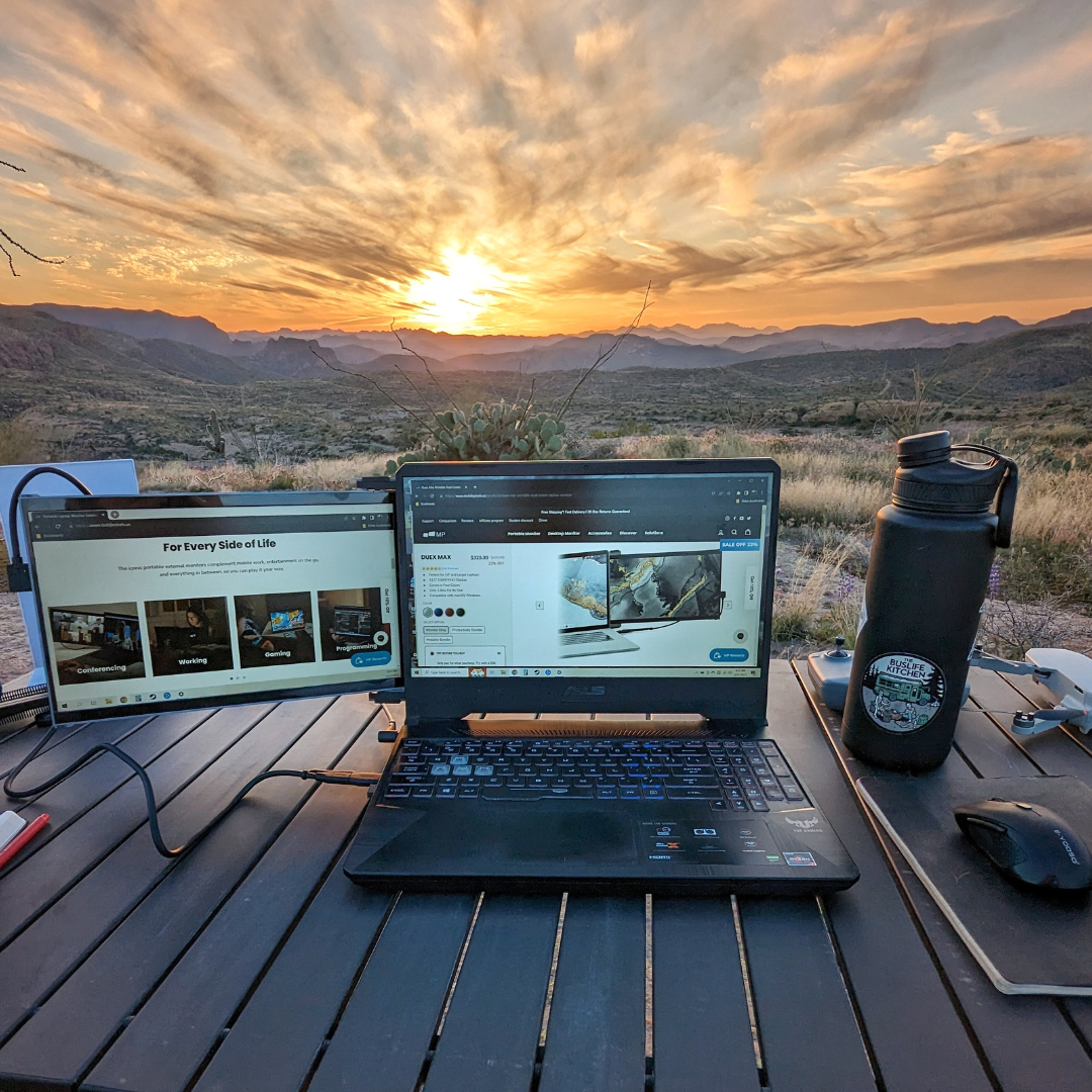 Setup de trabajo portátil con notebook y monitor Mobile Pixels en paisaje natural al atardecer