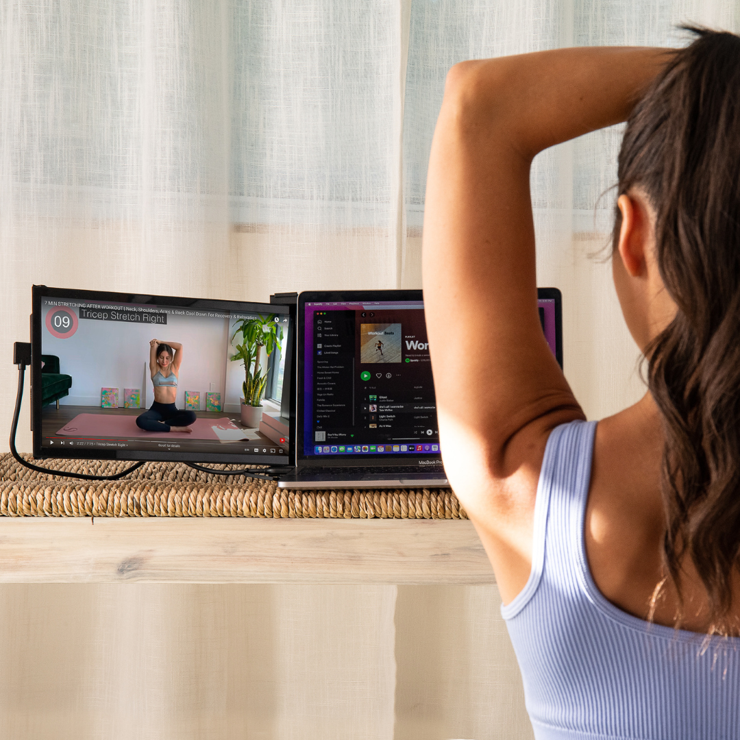 Mujer haciendo ejercicio frente a doble pantalla portátil con video de rutina de estiramiento
