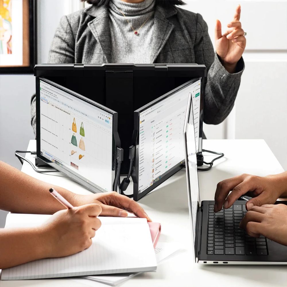 Monitor portátil Mobile Pixels Trio Max utilizado en reunión de trabajo para mostrar contenido a compañeros; triple pantalla acoplable ideal para presentaciones colaborativas, productividad en equipo y trabajo remoto con laptop.