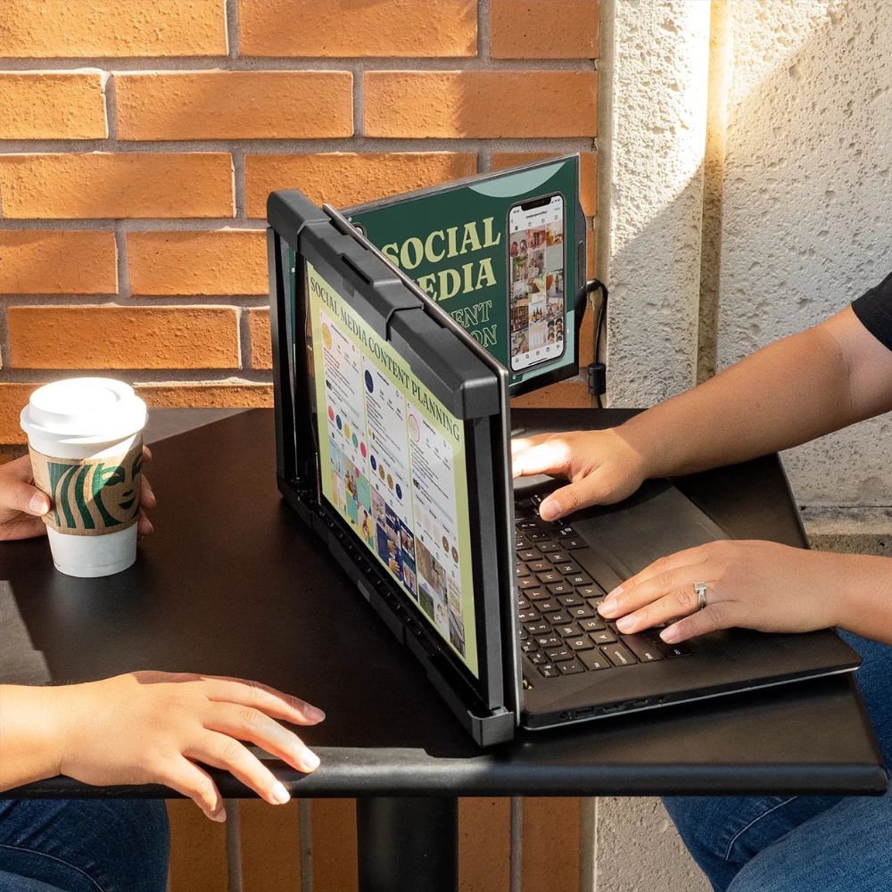 Estudiantes en una cafetería usando monitor portátil Mobile Pixels Trio Max en reunión de estudio para mostrar contenido a compañeros; triple pantalla acoplable ideal para trabajos en grupo, presentaciones académicas y productividad estudiantil desde laptop.