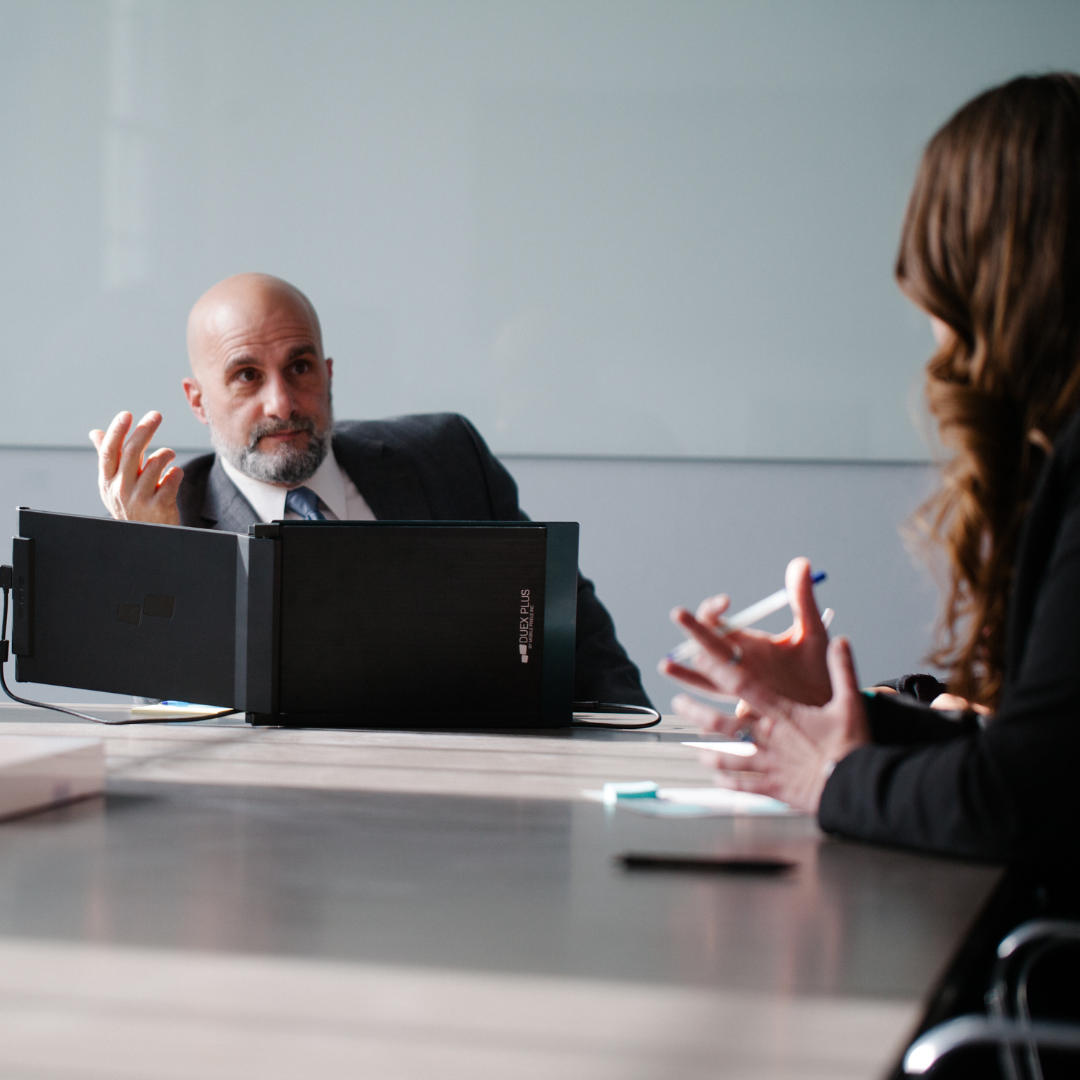 Ejecutivo frente a triple pantalla portátil Mobile Pixels liderando reunión de equipo