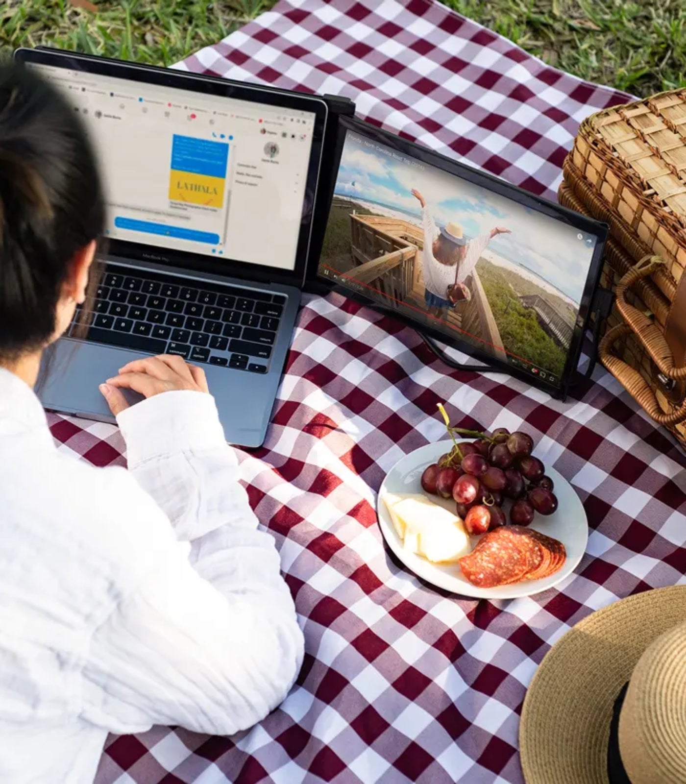 Persona trabajando al aire libre con monitor portátil Mobile Pixels Duex Max y laptop, mirando videos en pantalla extendida; solución ideal para productividad en movimiento, multitareas y entretenimiento desde cualquier lugar.