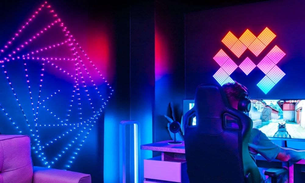 Setup gamer con luces LED inteligentes Twinkly creando efectos de color azul y rojo en la pared. Iluminación decorativa sincronizada con la estación de juego, ideal para streaming, gaming y espacios tecnológicos modernos.