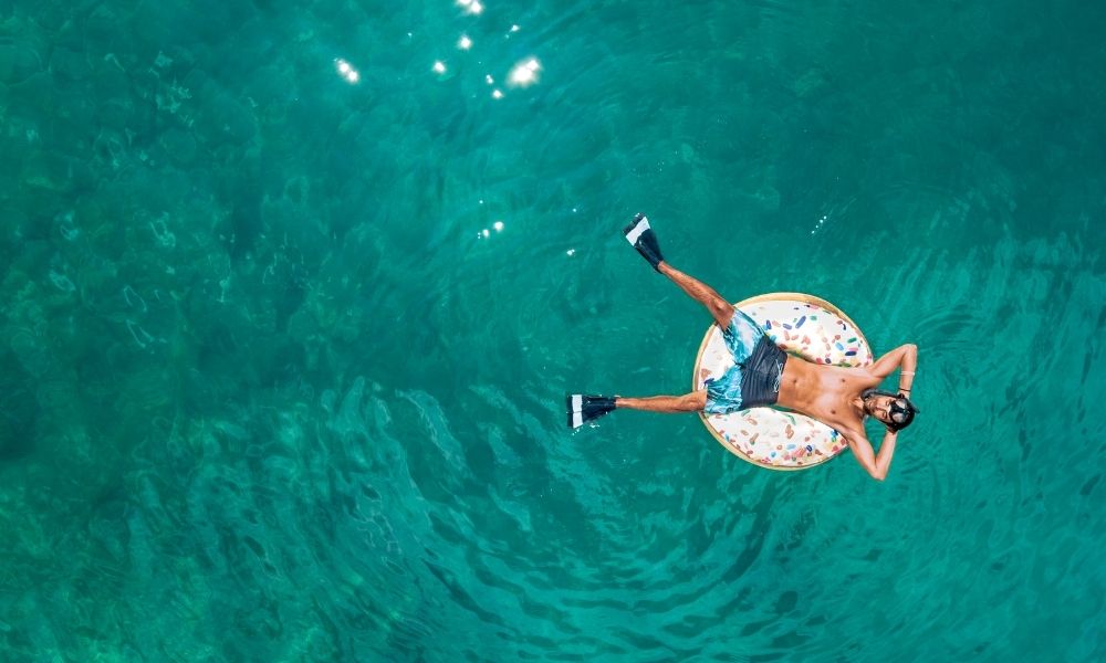 Persona relajándose durante las vacaciones de verano flotando sobre el mar turquesa con equipo de snorkel, representando descanso, desconexión y calidad de vida en la playa.