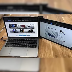 Cliente utilizando monitor portátil Mobile Pixels como pantalla adicional junto a su laptop para navegación web y comparación de productos; solución ideal para productividad y multitareas en entornos flexibles.