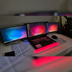 Cliente satisfecho con setup de laptop y doble monitor portátil Mobile Pixels Trio Max en escritorio gamer; estación de trabajo inmersiva con triple pantalla para productividad, entretenimiento y diseño visual.
